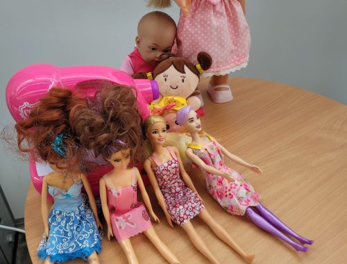 Zestaw lalek i maskotek przygotowanych do Kieleckiej Wymiany Zabawek – lalki Barbie, niemowlęta i zabawkowa suszarka.