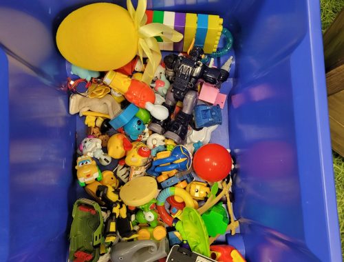 Plastikowy pojemnik z różnorodnymi drobnymi zabawkami zebranymi na Kielecką Wymianę Zabawek.